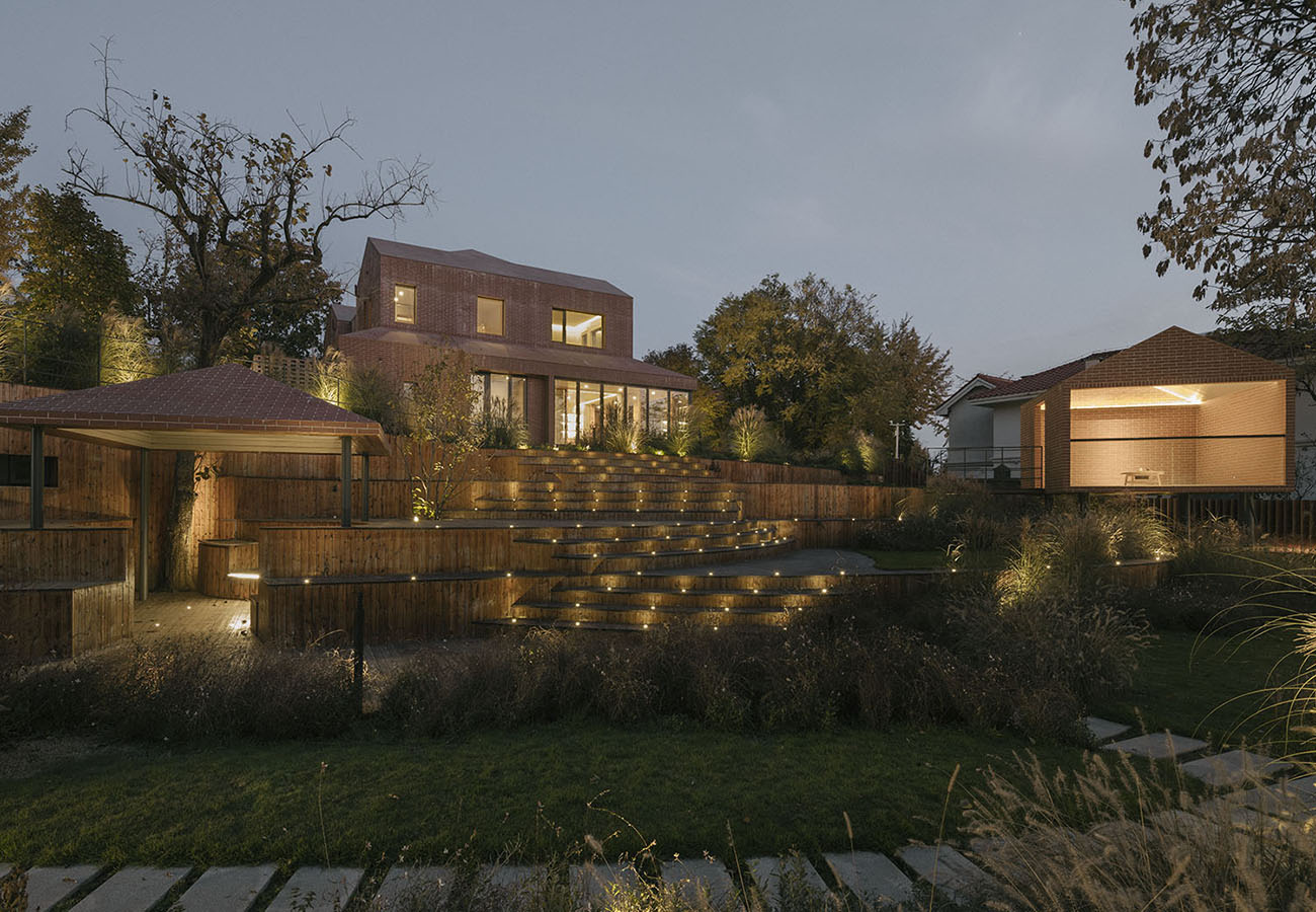 The garden landscape composed of a series of curved stairs remains connected to the interior of the house