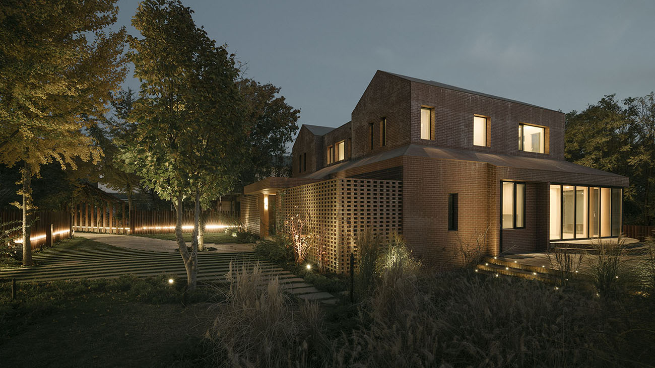 The blurry boundary between the outside and inside of the house is formed due to the glass openings and the holes in the red brick walls