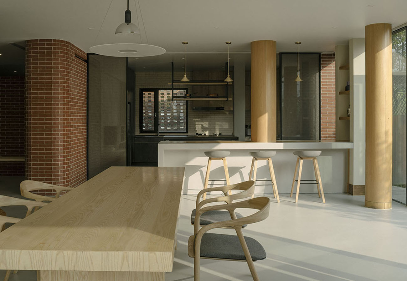 Together with concrete floors and columns, as well as upholstered furniture, red bricks make up the interior of the ground floor of the house