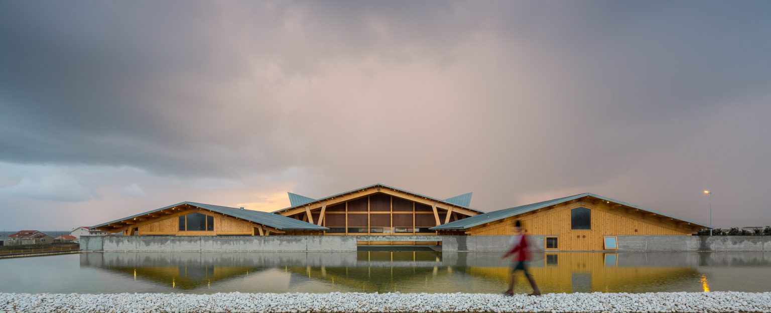 The wide span covered arena is the main volume of this equestrian center