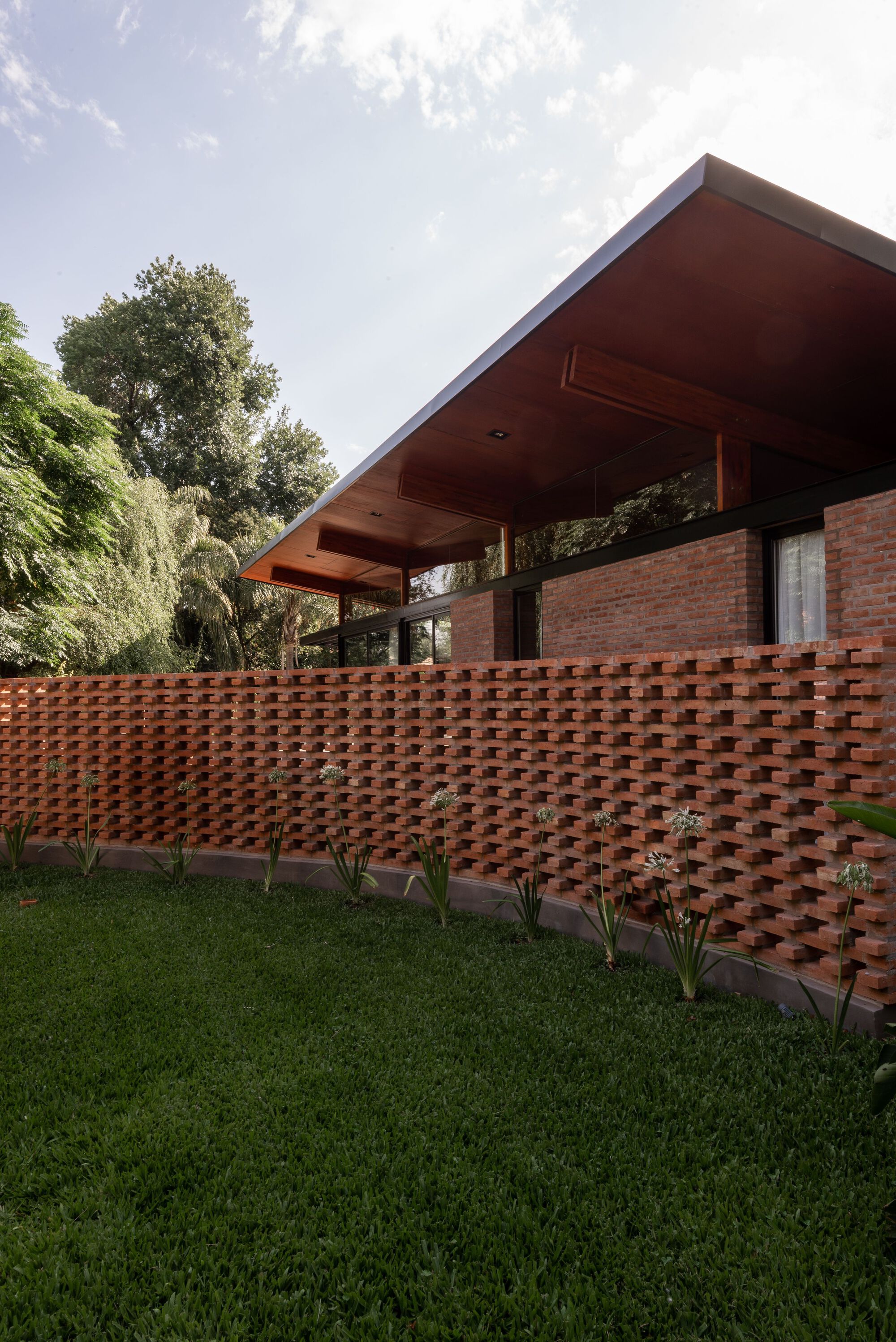 green garden with typical tropical plants and a reddish-brown house in a traditional-modern style