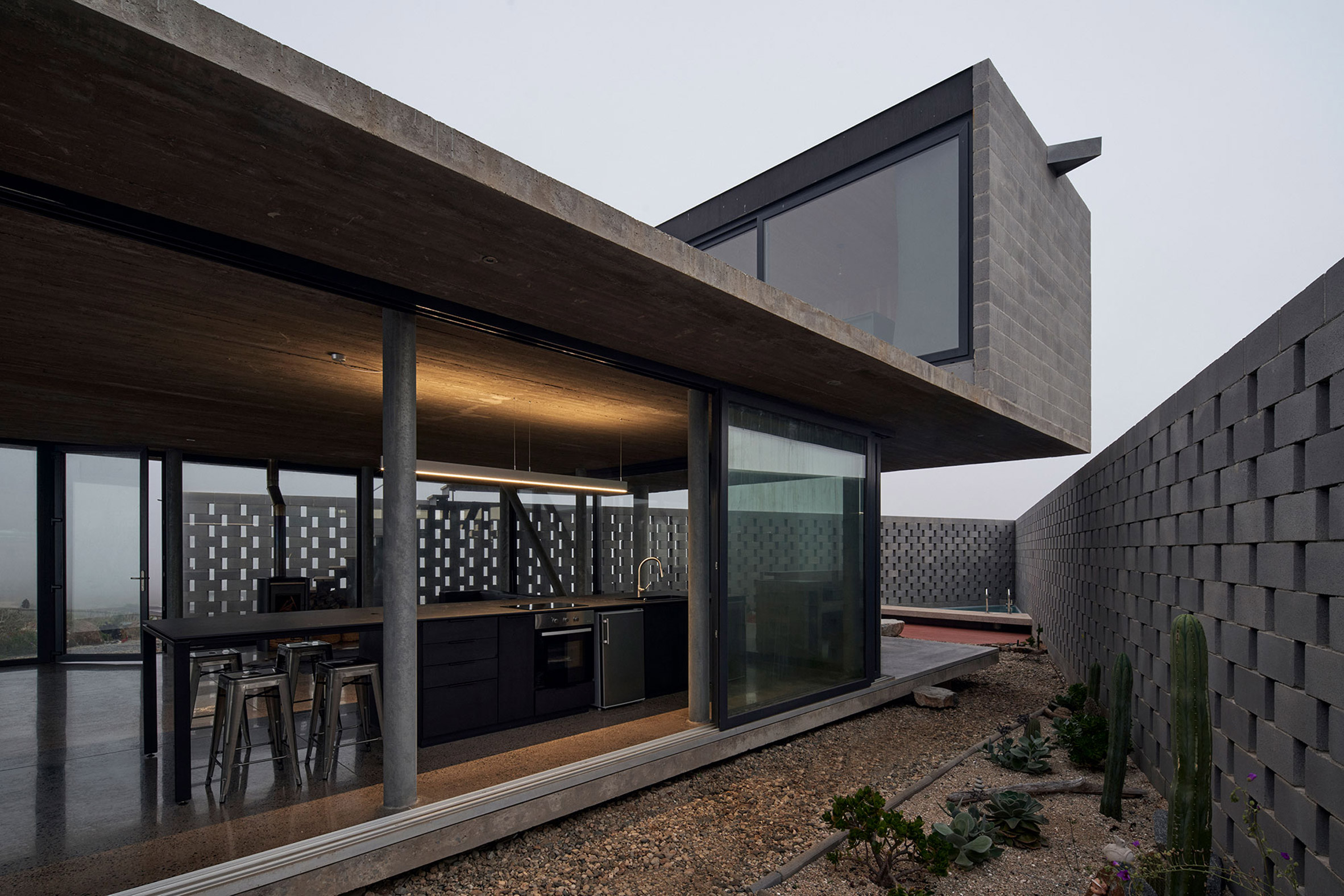 The backyard and interior of the LBS house are connected via a semi-open terrace that simultaneously extends the kitchen countertops for its bar benches.Â (Image courtesy ofÂ CristÃ³bal Palma)