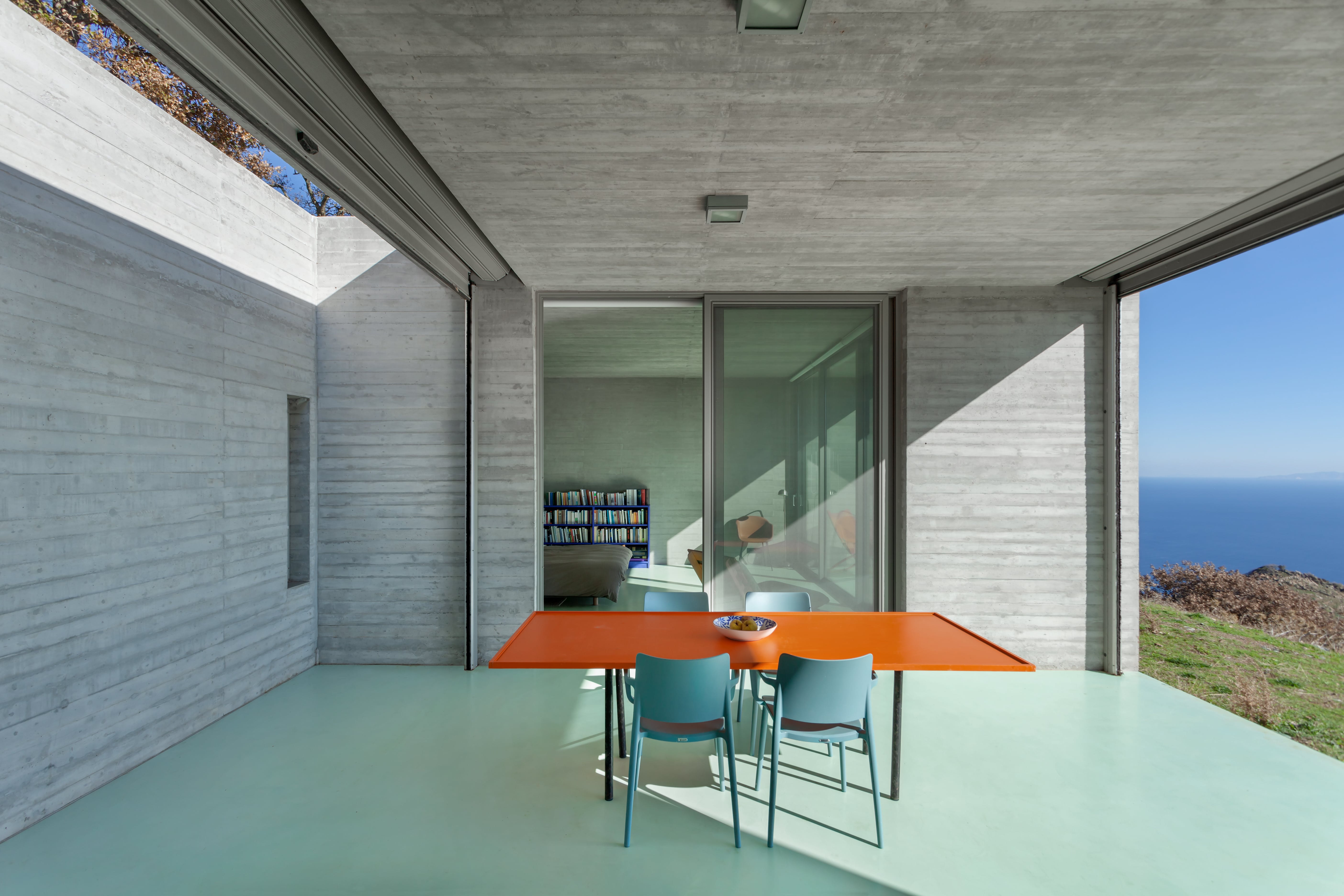 The dining room with wide windows and contrasting orange table